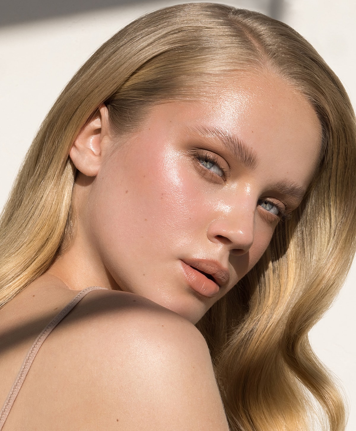 Close-up of woman with glowing skin and wavy hair.