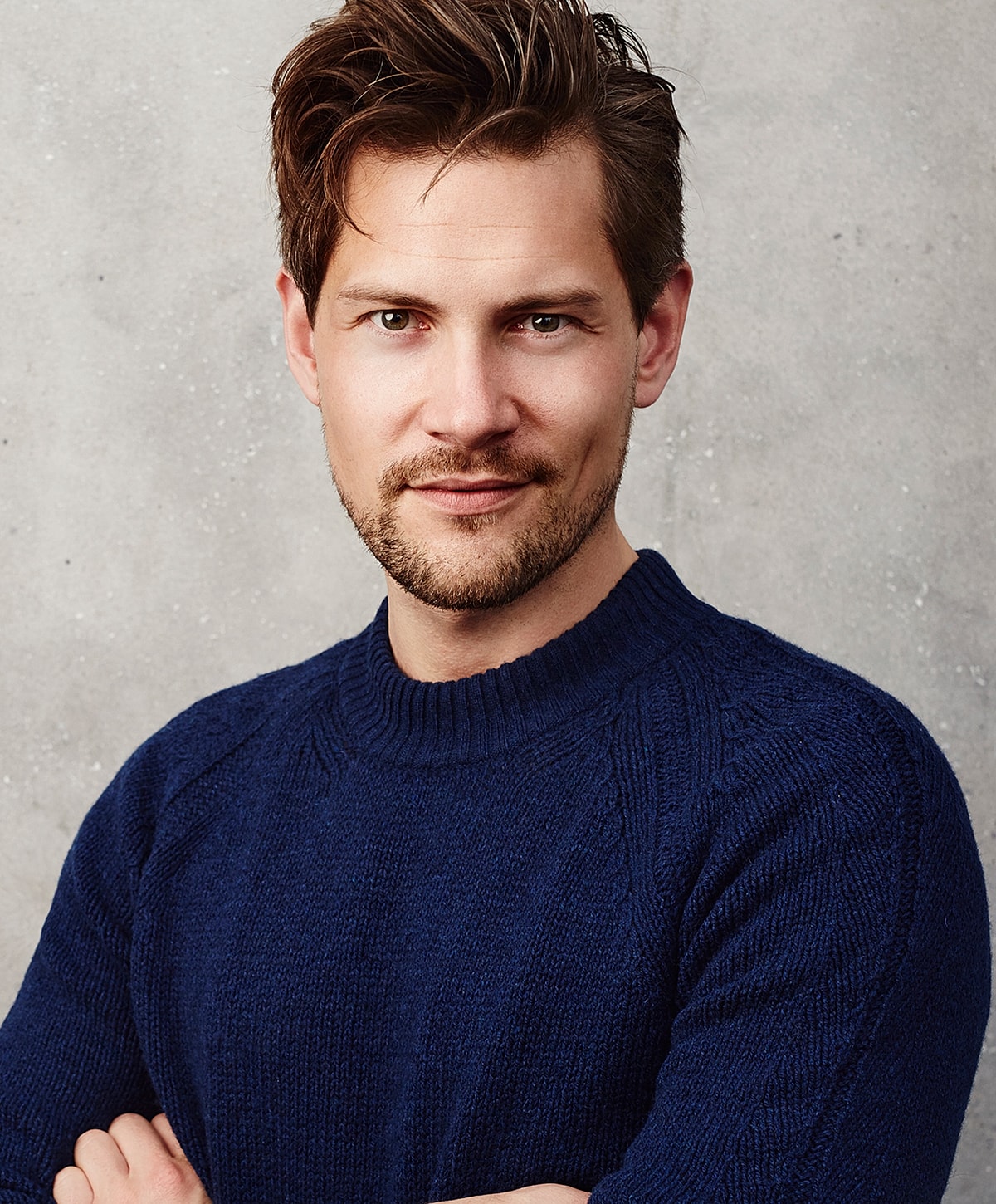 Man with stylish hair in navy sweater.