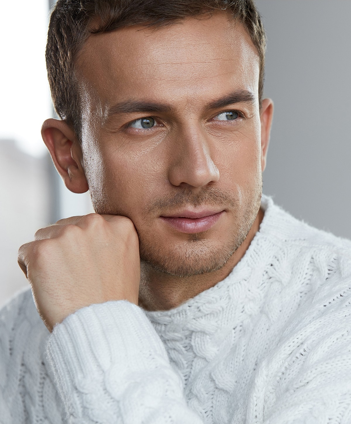 Man in white sweater with thoughtful expression.