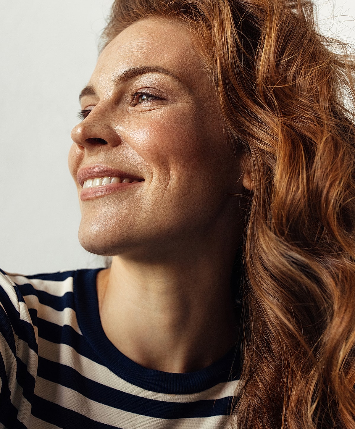 Woman with wavy red hair smiling gently.