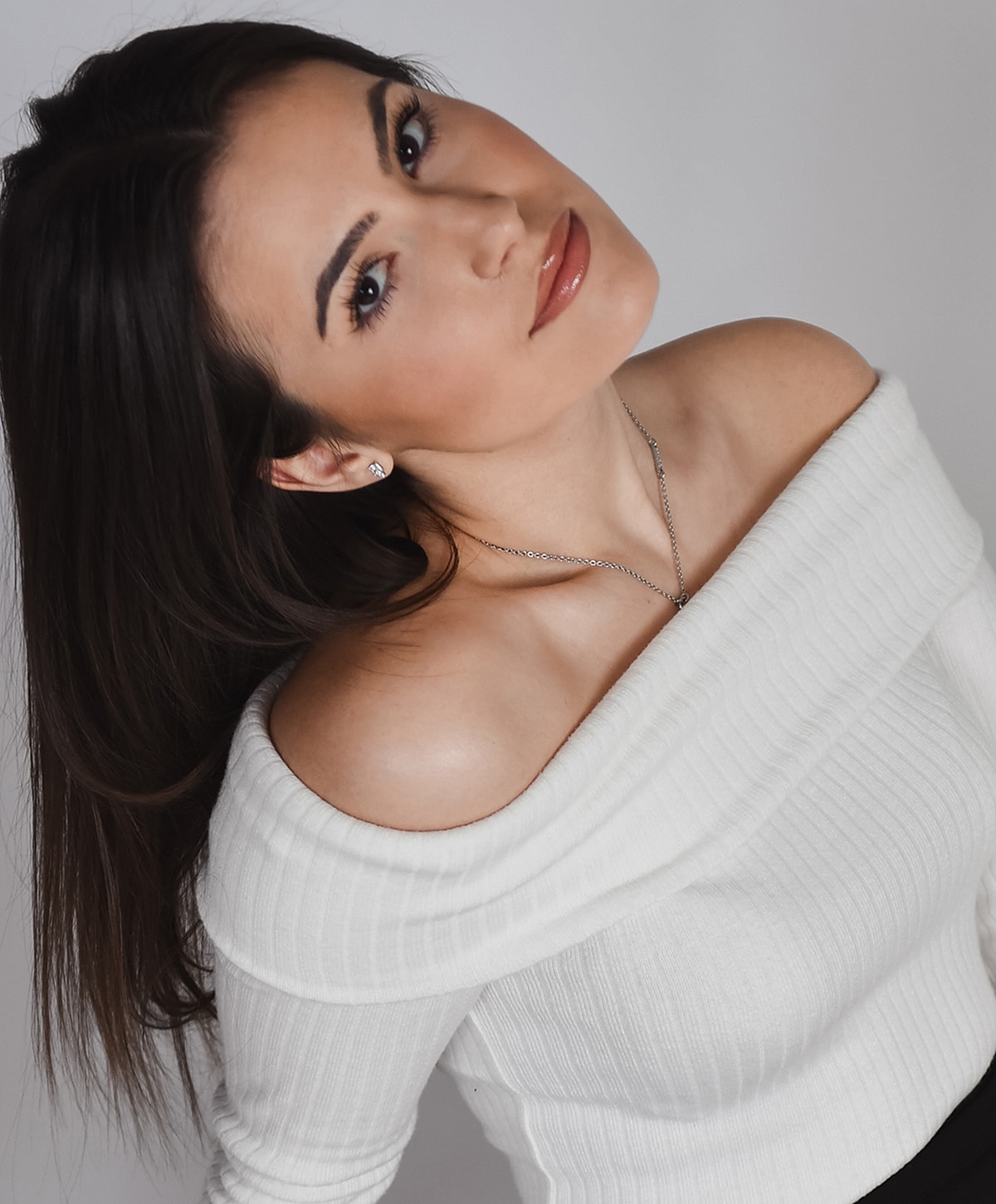 Woman in off-shoulder white sweater, portrait.