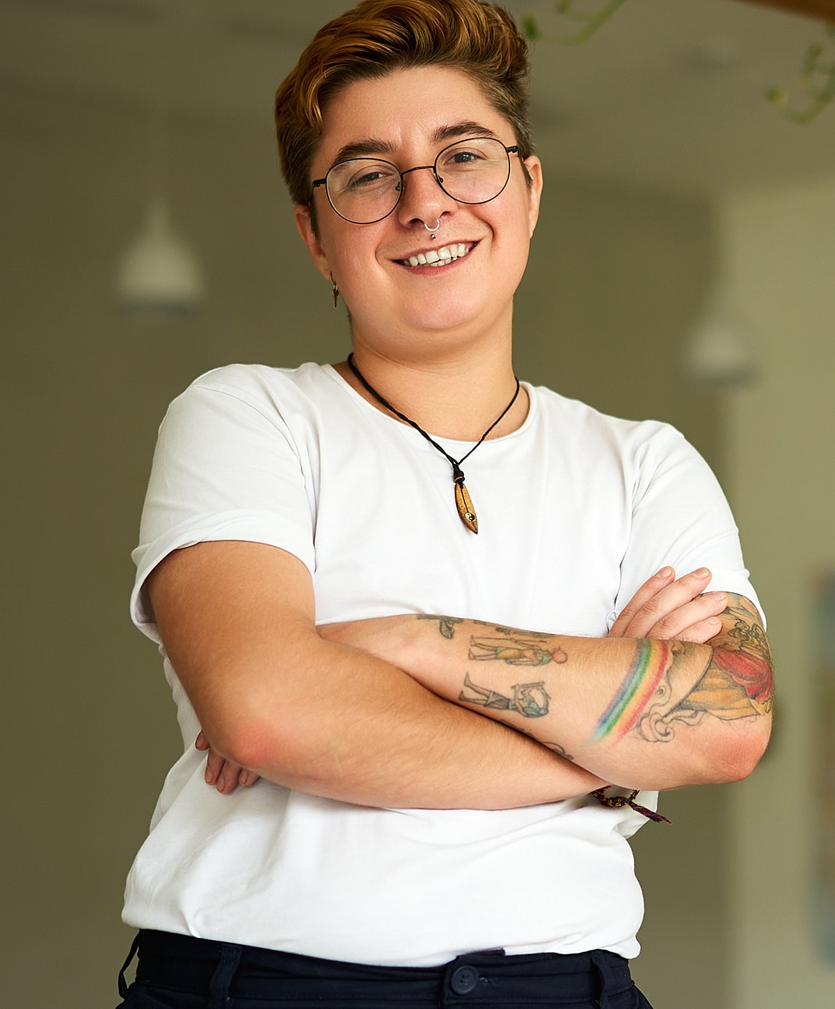 Smiling person with tattoos, wearing glasses.