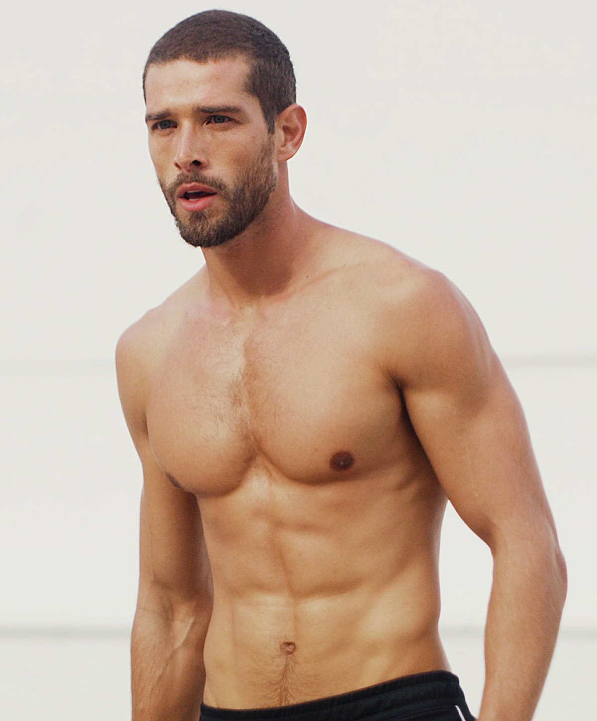 Shirtless man outdoors with a serious expression.