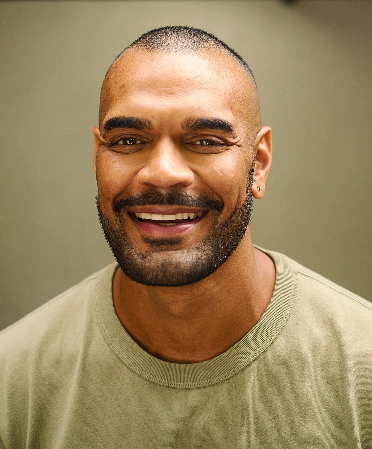 Smiling man in green shirt against neutral background.