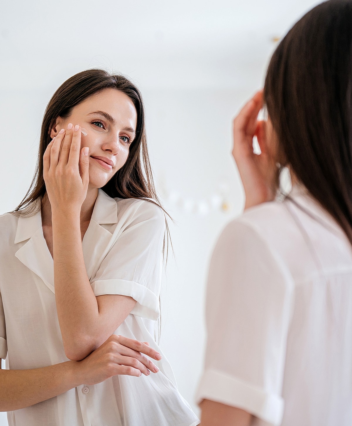 Woman applying skincare while looking in mirror