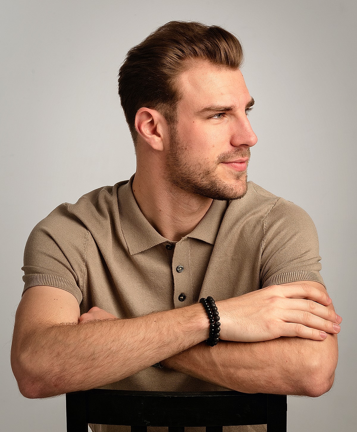 Man in beige polo shirt with arms crossed.