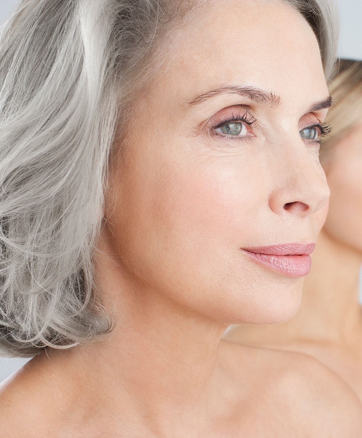 Elegant woman with gray hair and natural makeup.