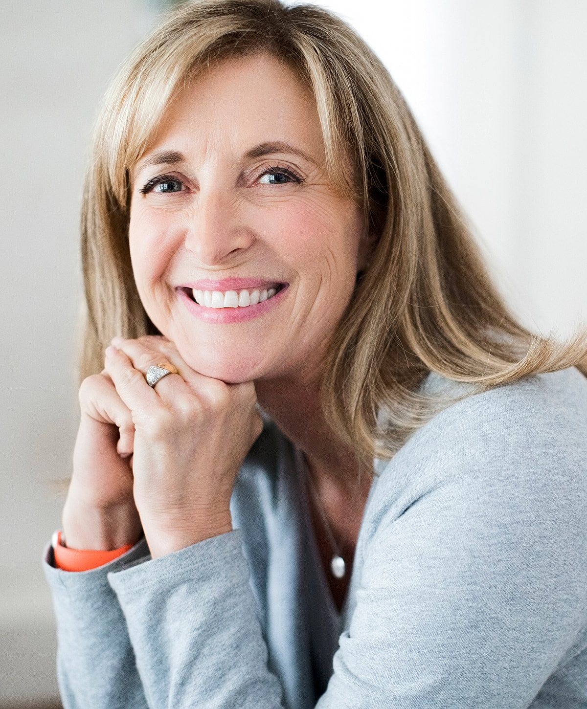 Smiling woman resting chin on hands.