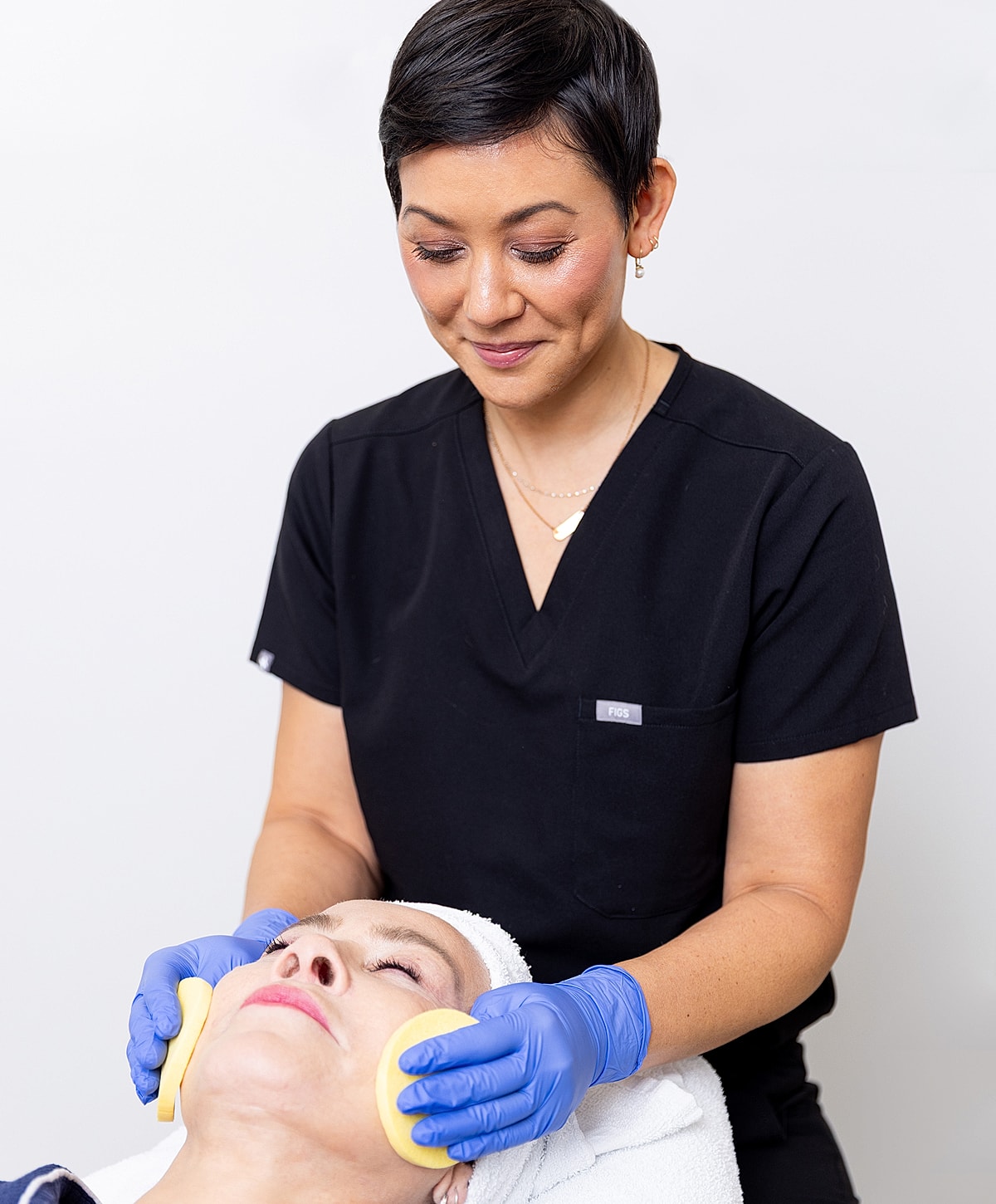 Aesthetician providing facial treatment to client.
