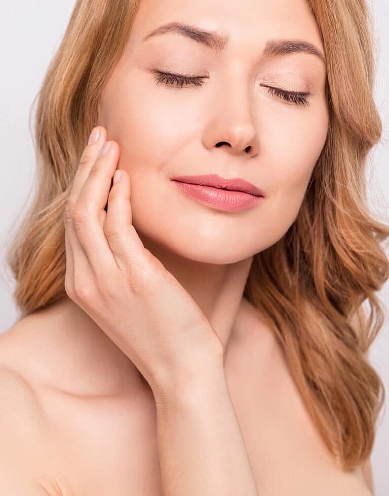 Woman with closed eyes showcasing skincare routine.