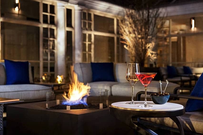 Cozy outdoor seating with drinks and fire pit.