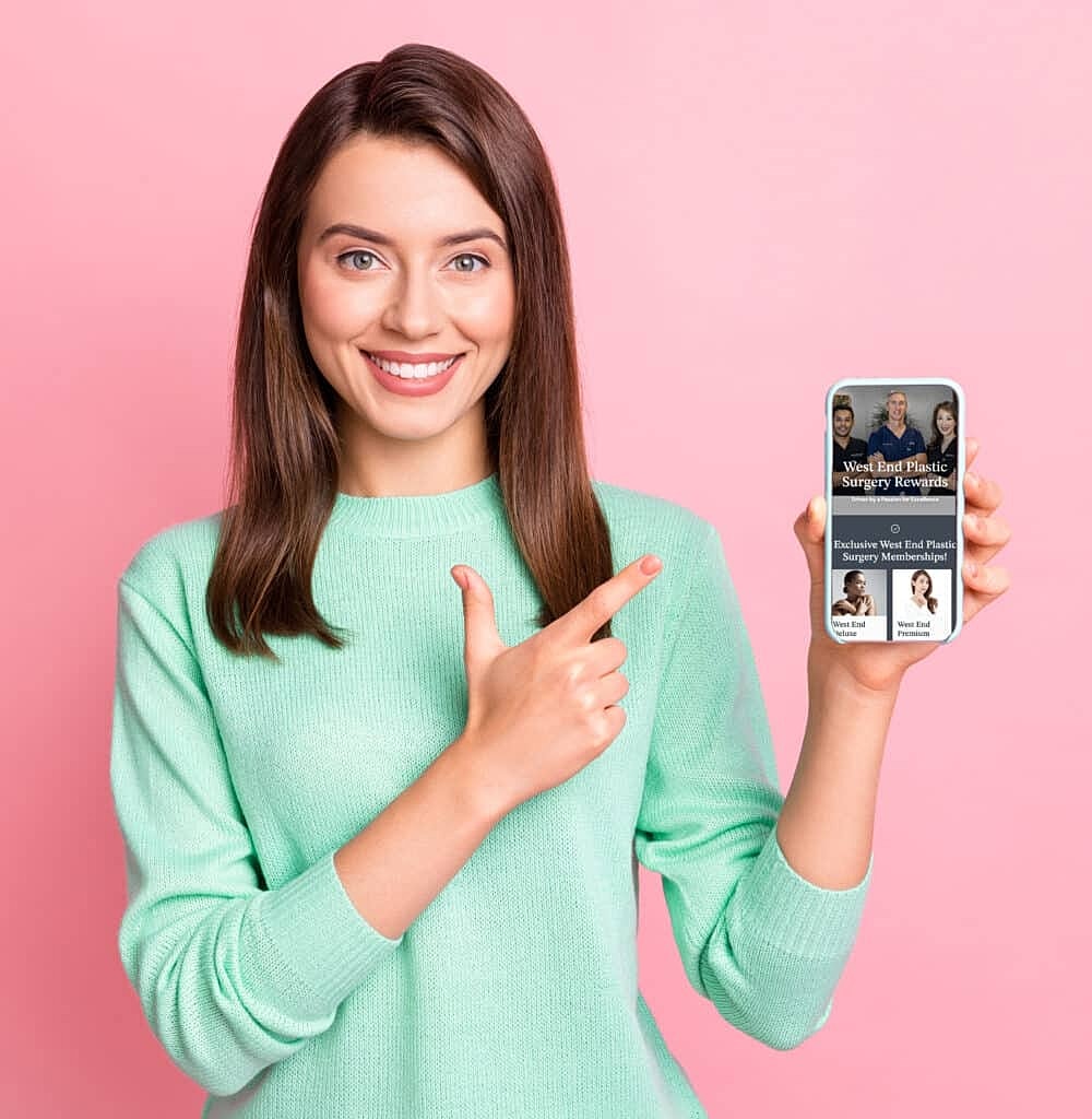 Photo of cute young lady hold telephone direct finger screen empty space wear teal pullover isolated pink color background