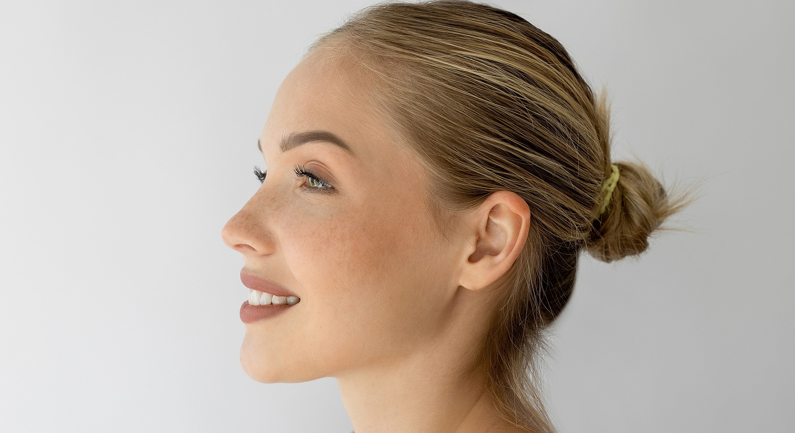 Profile of a smiling woman with natural makeup.