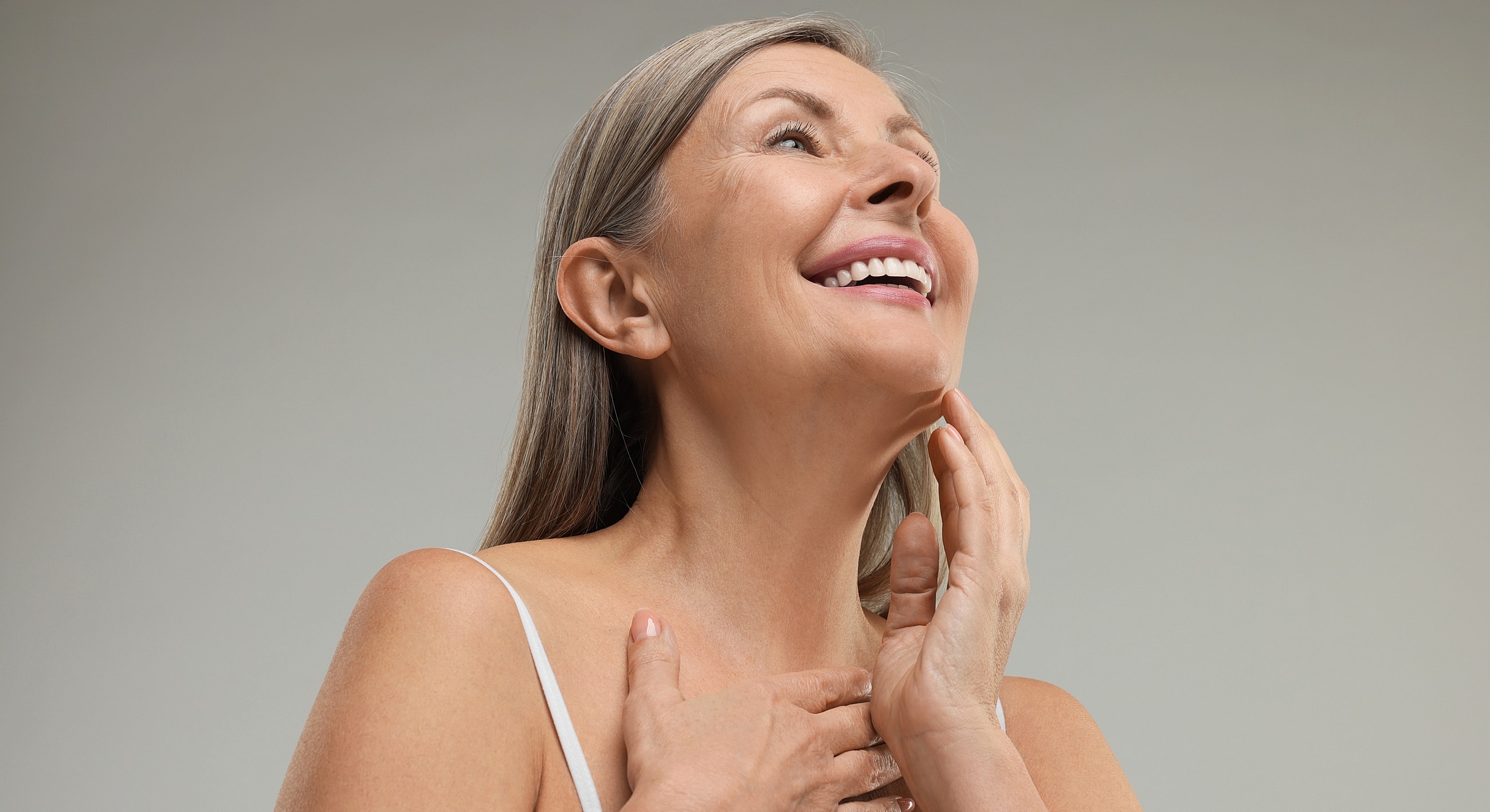 Smiling woman touching her face, promoting skincare.