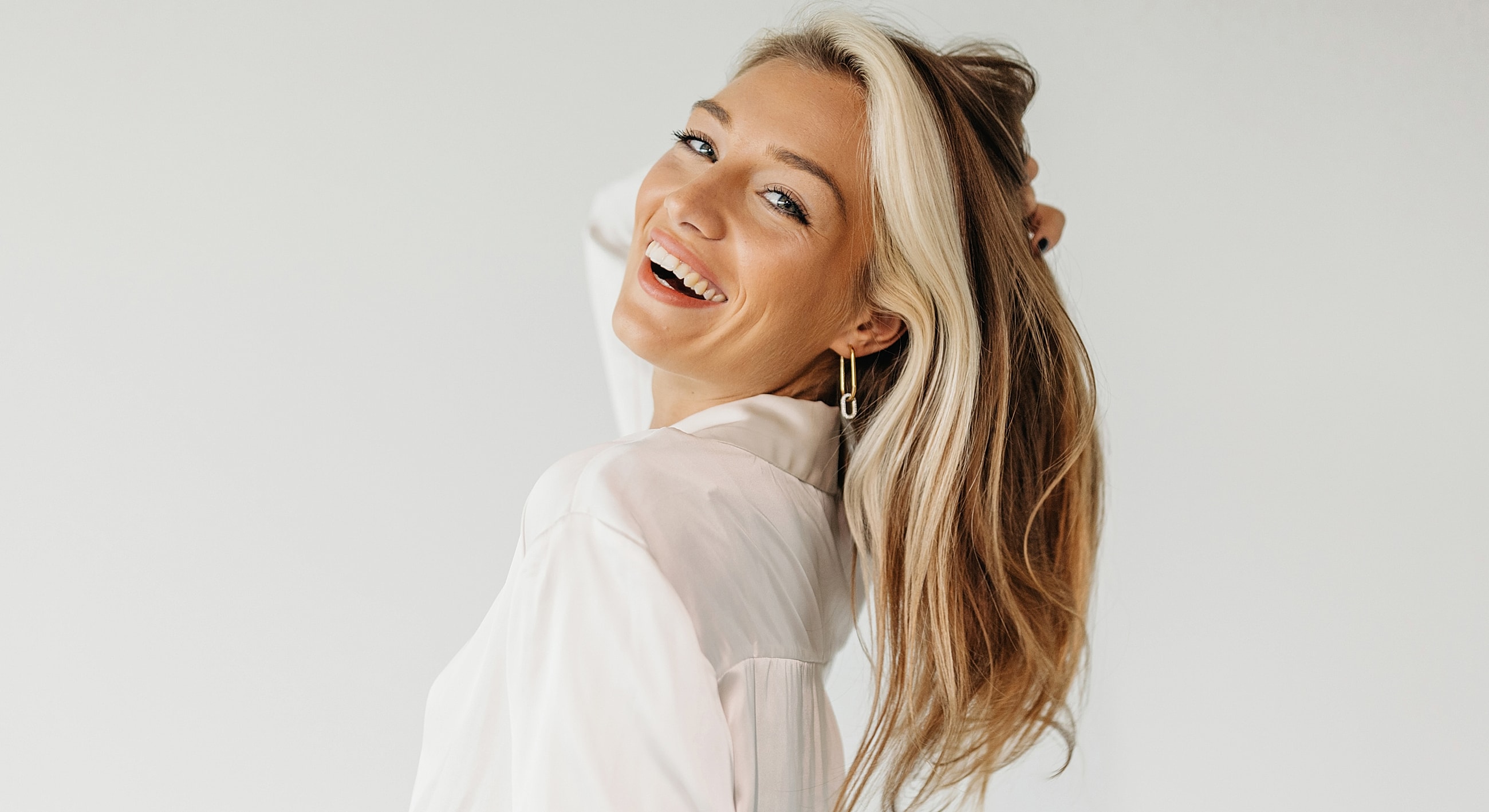 Smiling woman with long hair against plain background.