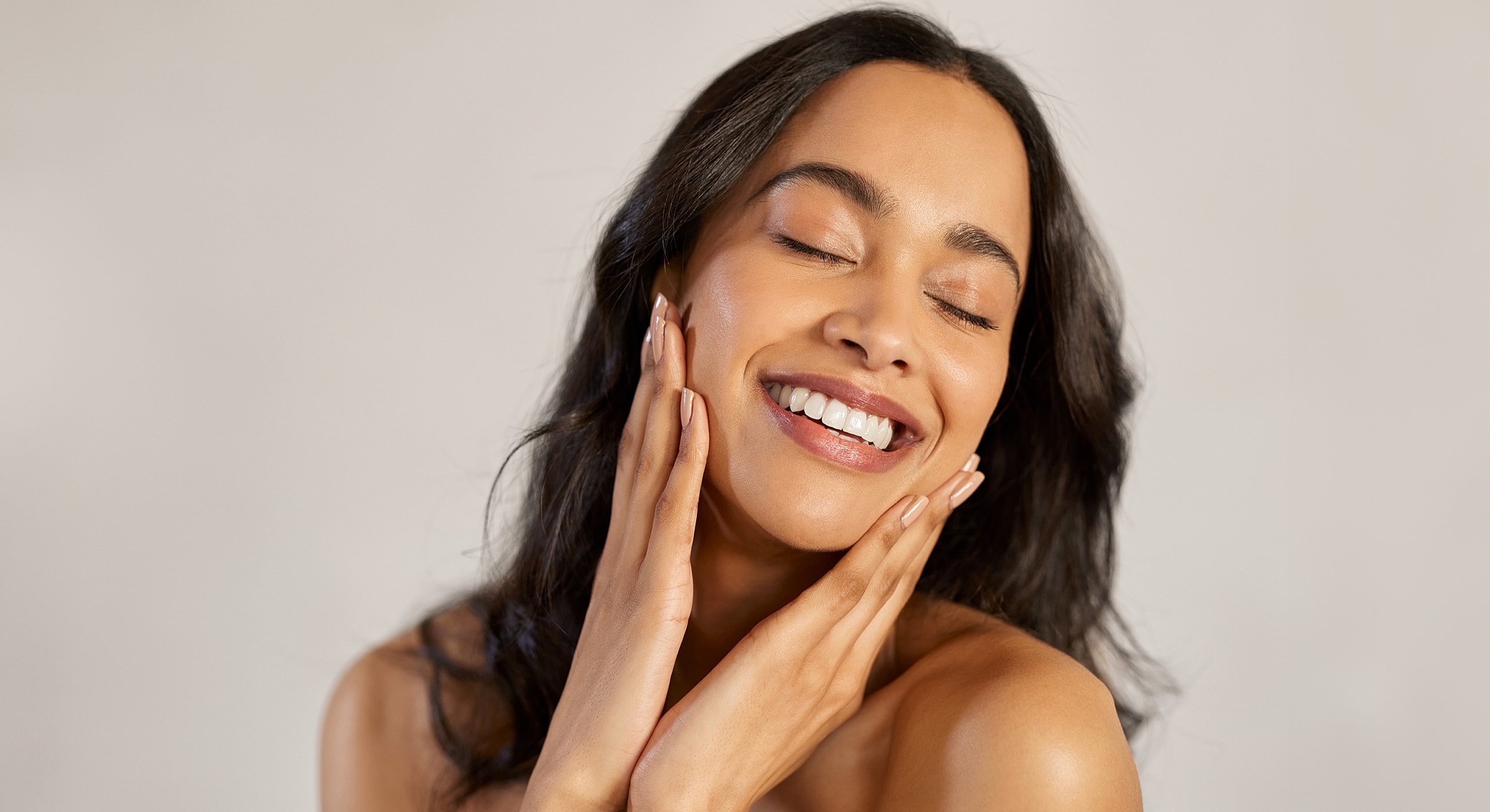 Smiling woman touching her face gently.