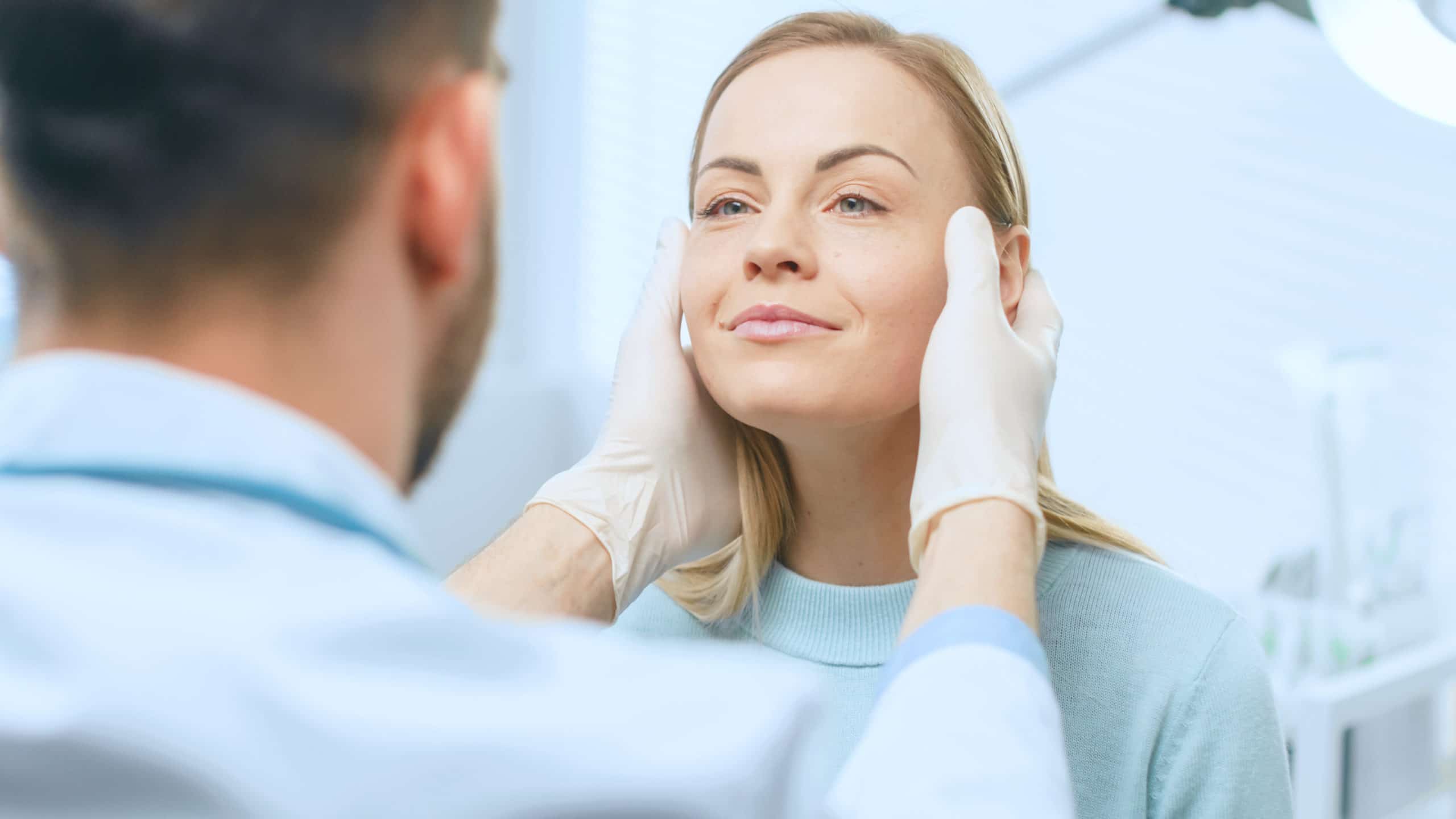 Plastic / Cosmetic Surgeon Examines Beautiful Woman's Face, Touches it with Gloved Hands, Inspecting Healed Face after Plastic Surgery with Amazing Results. Plastic / Cosmetic Surgeon Examines Beautiful Woman's Face, Touches it with Gloved Hands, Inspecting Healed Face after Plastic Surgery with Amazing Results.