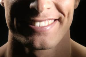 close up on the chin, mouth, teeth and nose of a smiling man with