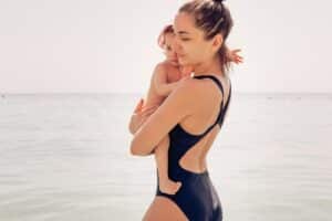 Mom with a little daughter are waist deep in the sea water.