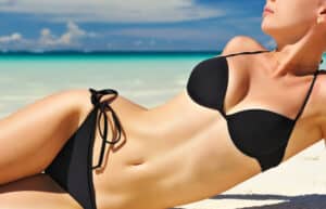 Woman with natural-looking breast augmentation on a beach in a bikini