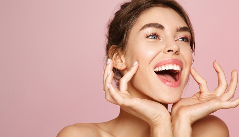 Beautiful woman smiling and touching her face after facial cosmetic surgery in Washington, DC