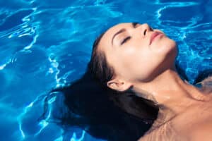 Woman in pool with slim, contoured face from buccal fat removal in Washington, DC