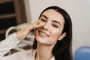 Smiling woman touching her nose after rhinoplasty in Washington, DC